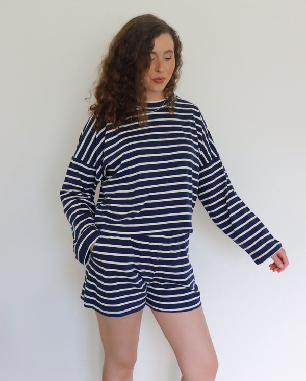 Woman wearing a navy and white striped outfit against a plain background