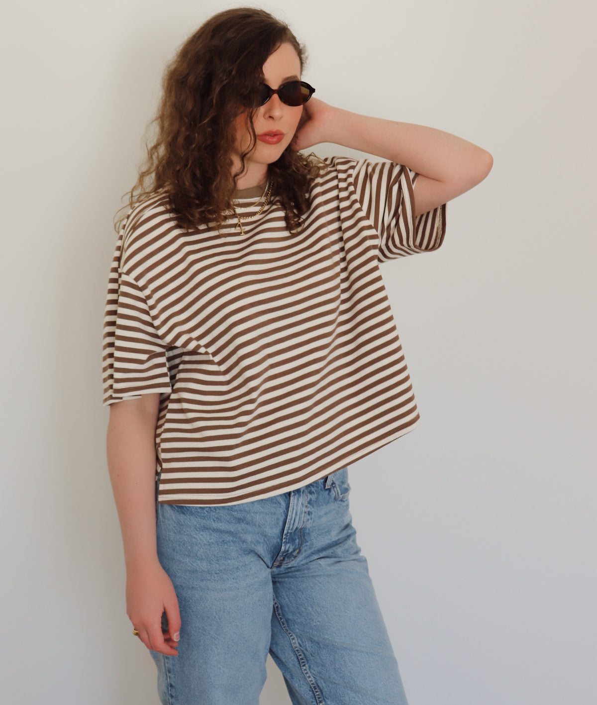 A woman wearing jeans and a brown and white striped tee