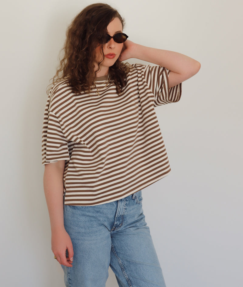 A woman wearing jeans and a brown and white striped tee