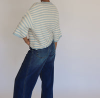 Woman wearing a striped cardigan and jeans against a plain background