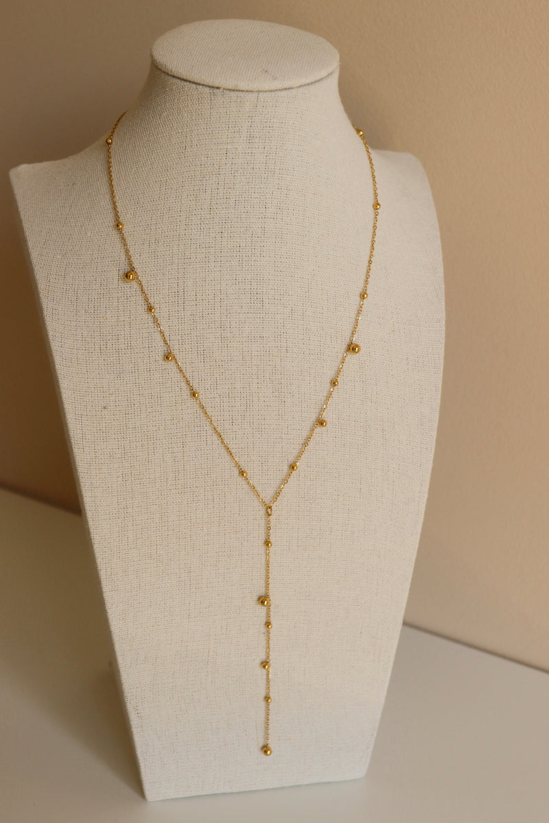 Gold necklace on a mannequin bust against a beige background