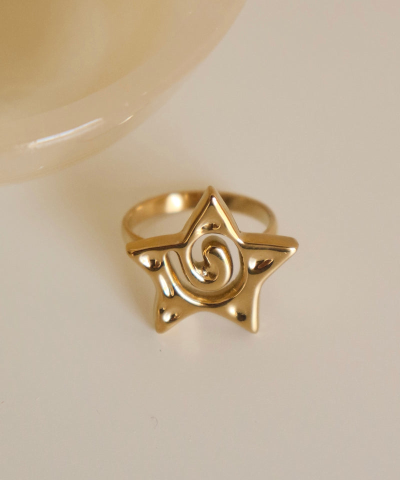 Gold ring with a spiral/star design on a light background