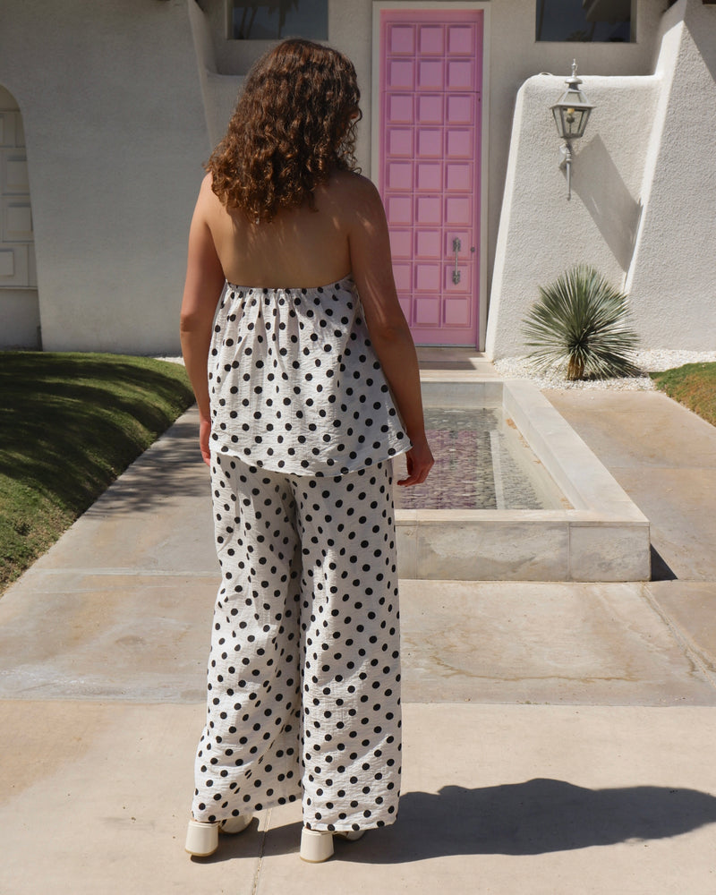 Woman in a polka dot set standing in front of a pink door.
